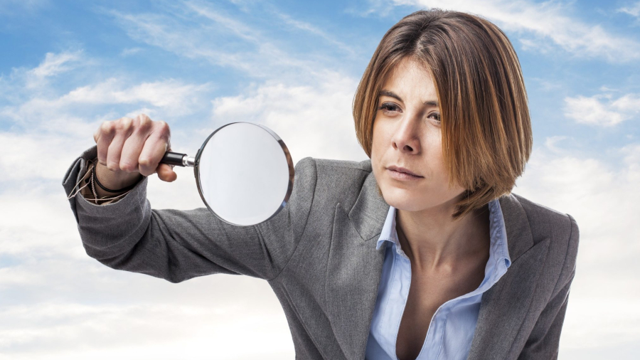 portrait of an executive young woman looking through a magnifying glass