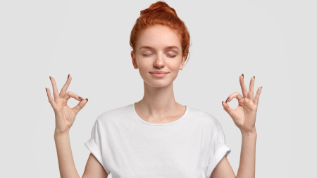 People, yoga and mediatation concept. Relaxed foxy girl with freckled soft skin enjoys peaceful atmosphere, keeps hands in mudra sign, relaxed after intense day, isolated over white background