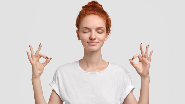 People, yoga and mediatation concept. Relaxed foxy girl with freckled soft skin enjoys peaceful atmosphere, keeps hands in mudra sign, relaxed after intense day, isolated over white background