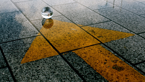 A high angle shot of the stone ground with a yellow arrow pointing towards a mysterious crystal ball