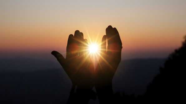 Faith of christian concept: Spiritual prayer hands over sun shine with blurred beautiful sunset background